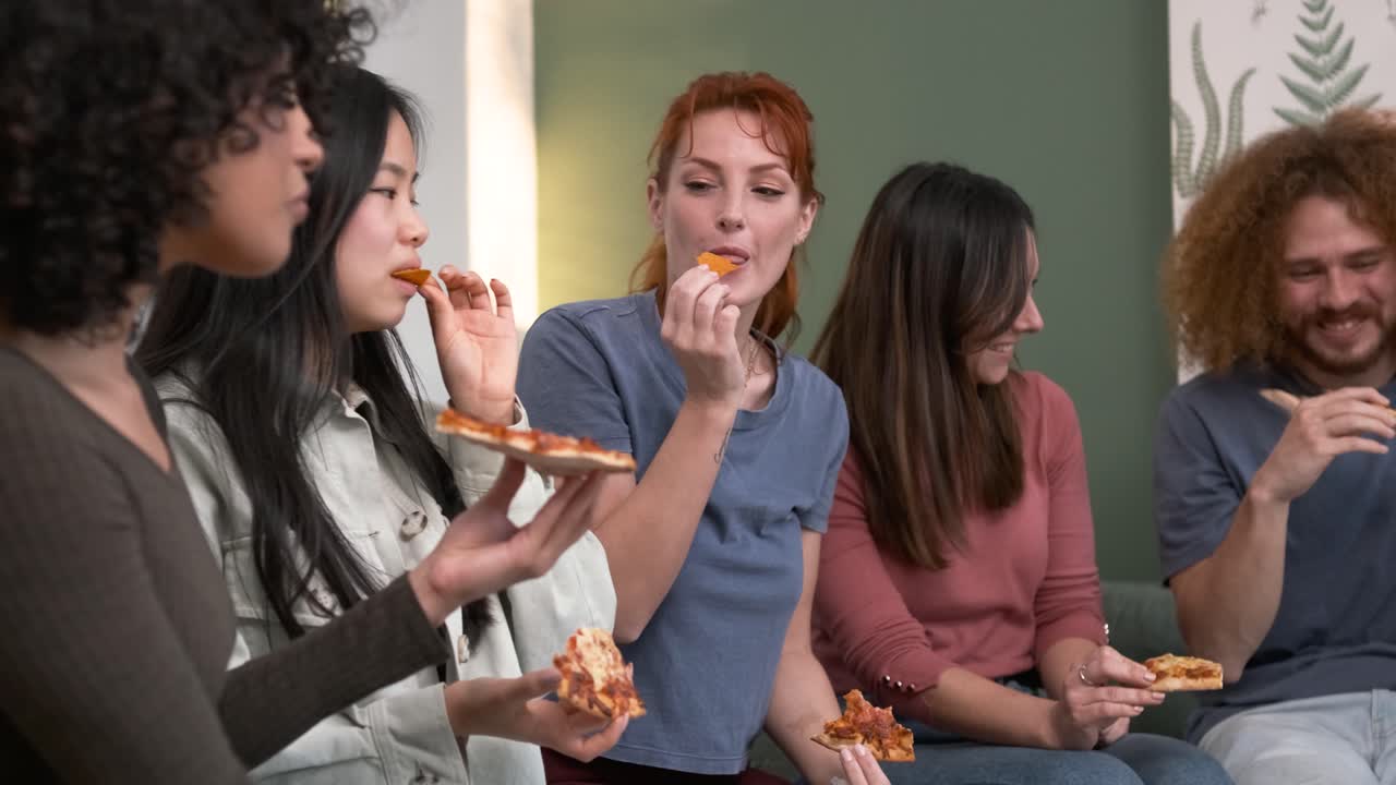 Diverse friends cheering up for woman bringing pizzas during weekend party at home