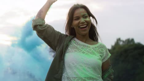 una mujer multirracial bailando con bombas de humo de colores en el festival de holi, filmada con una cámara de helio rojo en 8k.