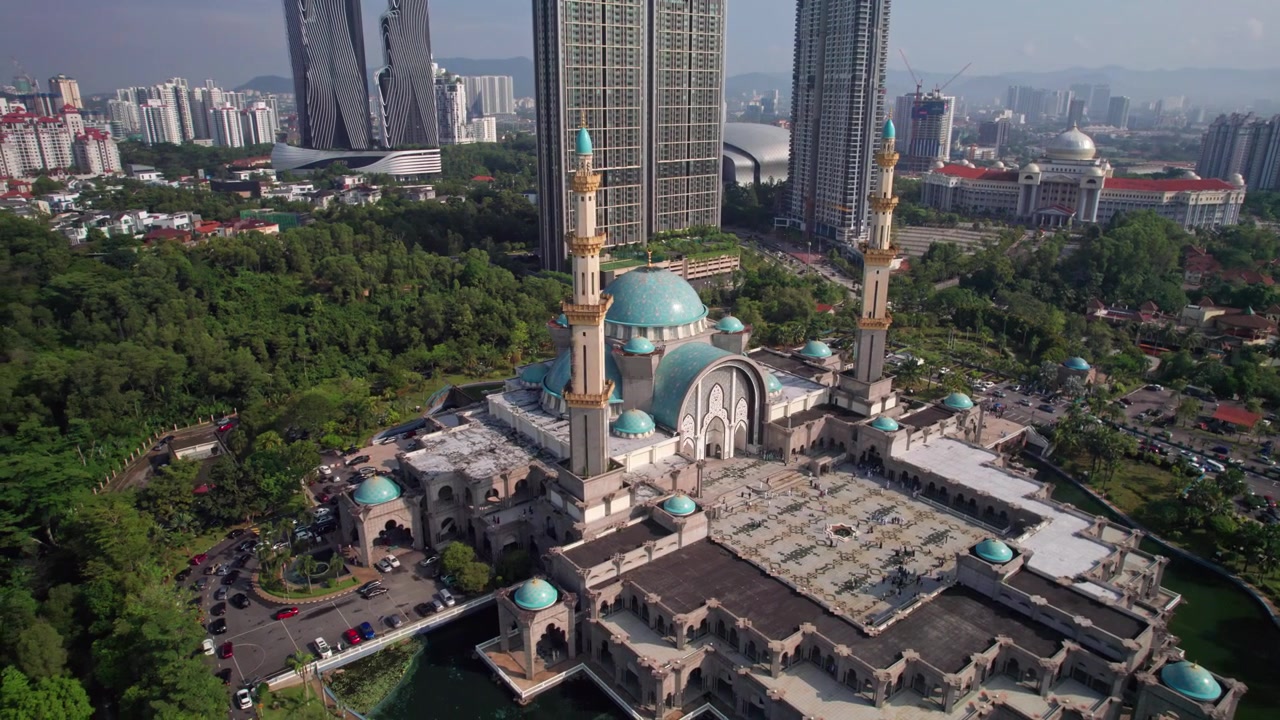 Rekaman udara sinematik yang naik di samping Masjid Wilayah Federal, menampilkan arsitektur Islam dan cakrawala kota terdekat di Malaysia