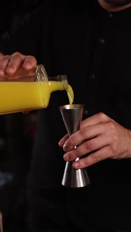 bartender pouring orange juice into a jigger