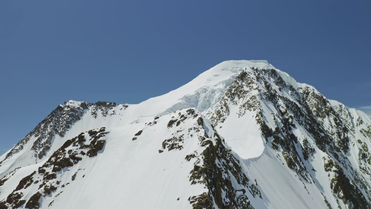 el avión no tripulado gira en círculos alrededor de la nieve perfecta la cumbre de la montaña blanca brilla sobre el cielo azul