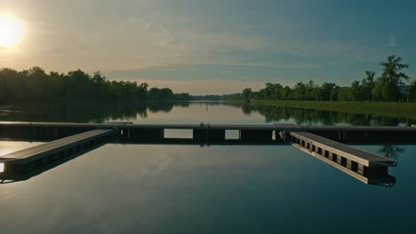 Calm-lake-with-docks-at-sunset,-reflecting-trees-and-a-clear-sky-at-Jarun-Lake,-Zagreb-Croatia