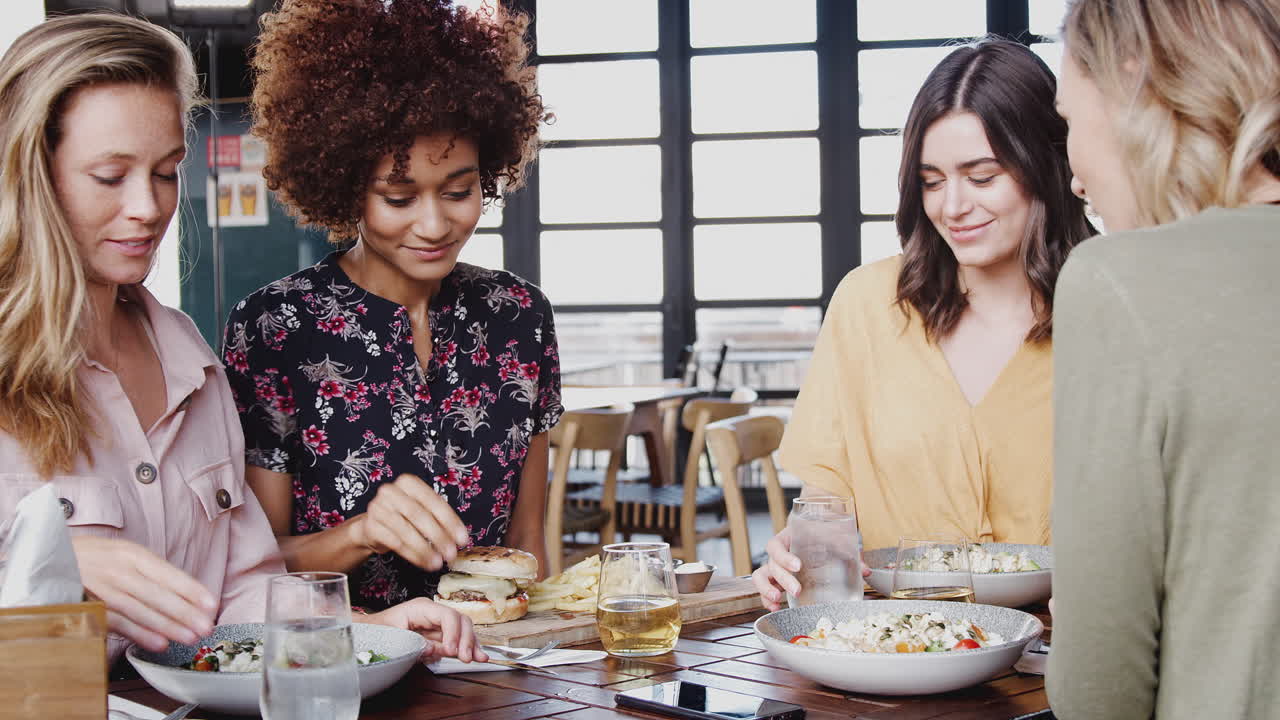 Four Young Female Friends Meeting For Drinks And Food In Restaurant
