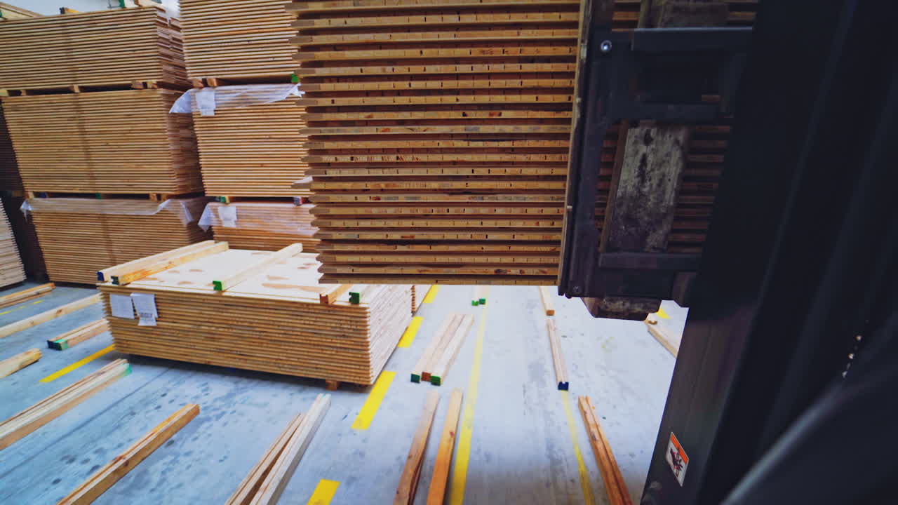 Wooden production. Forklift carries a wooden boards through the warehouse. Bunch of wooden panels moving on a truck inside the workshop.