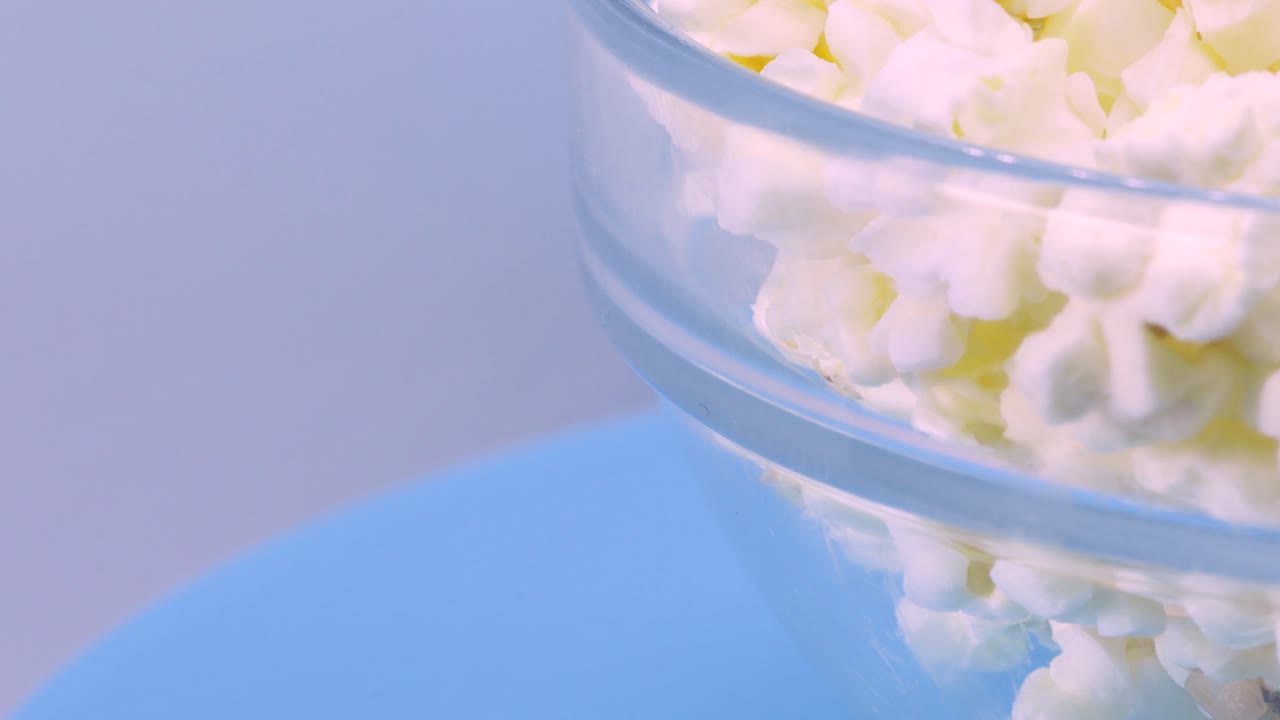 파란색 표면 위로 회전하는 팝콘 그릇, 4k의 매크로 샷