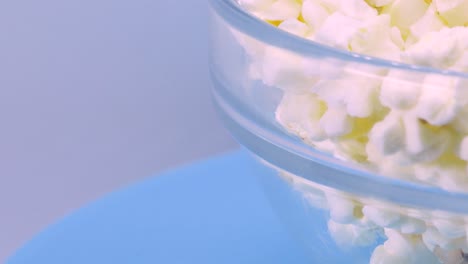 bowl of popcorn rotating over a blue surface, macro shot in 4k