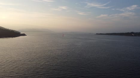 Approaching-lonely-sailboat-in-beautiful-sunset-at-sotra-Norway---Aerial-showing-sailing-boat-enjoying-freedom-at-sea-in-beautiful-evening---Norway