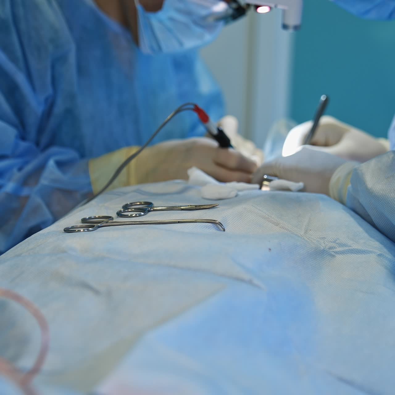Tools are lying on the patient during the surgery. Doctors work at backdrop. Nurse's hands puts the instruments for surgeons