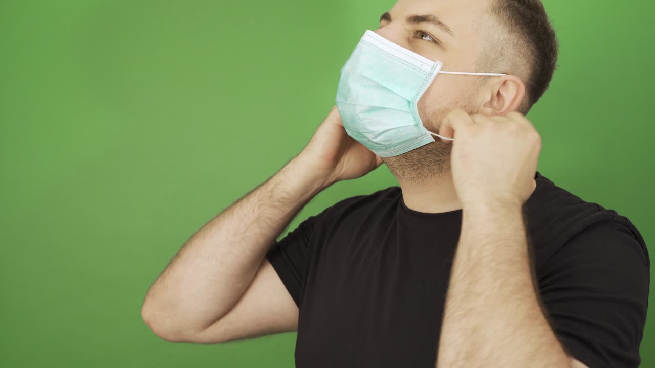 hombre caucásico quitándose los guantes de protección y la máscara facial y sonriendo. fin del concepto de pandemia o cuarentena. imágenes de pantalla verde.