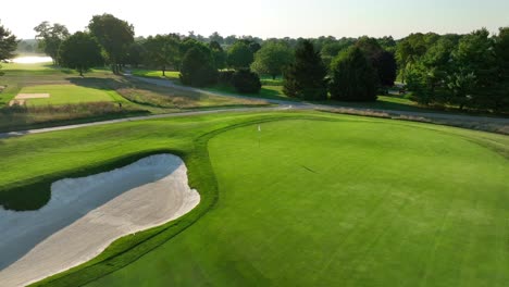 Golfplatz-Bei-Sonnenuntergang-Im-Sommer-Luftaufnahme-Eines-Sandbunkers-Und-Eines-Gepflegten-Grüns-Mit-Flagge-Am-Loch