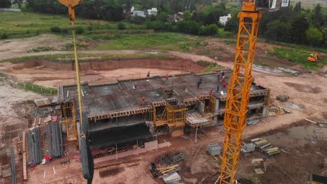 aerial view capturing the movement of a crane, transporting construction materials behind