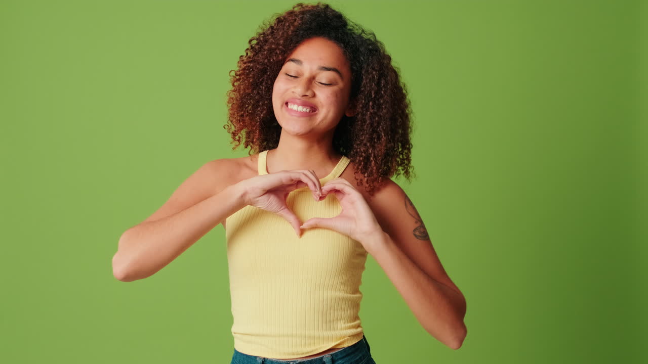 Giovane donna felice che forma un cuore con le mani