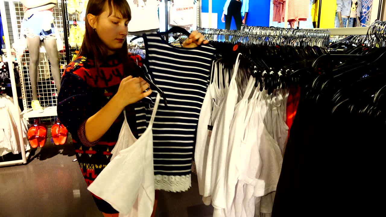 유럽의 쇼핑몰에서 소녀는 옷을 선택합니다.