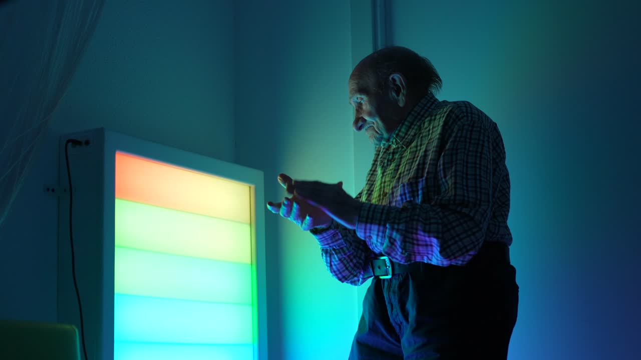 Uomo anziano in piedi in una stanza con luci colorate