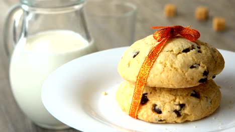 delicious sweet chocolate-chips cookies with an orange ribbon. milk-jug, on wooden table. looped