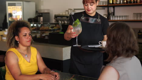 Dos-Mujeres-Hablando-Y-Sentadas-En-Una-Mesa