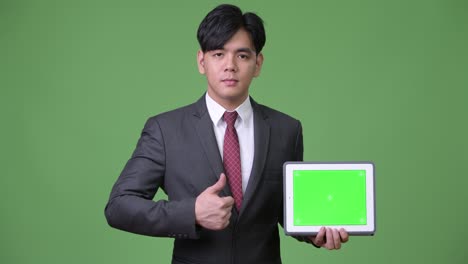 디지털 태블릿을 사용하는 젊은 잘생긴 아시아 사업가