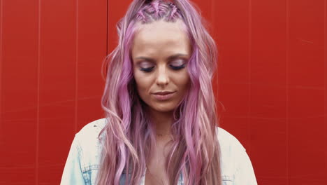 Woman with pink hair in front of red wall