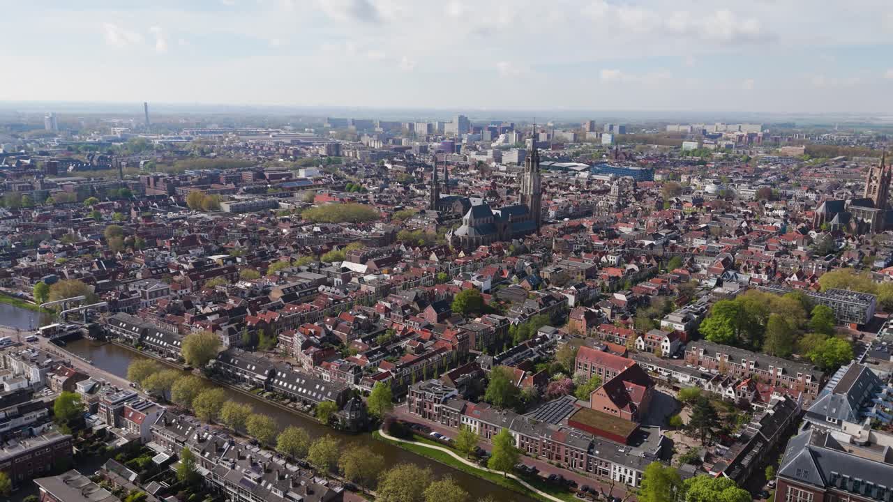 A wide aerial shot over a historic European city with red rooftops and canals.