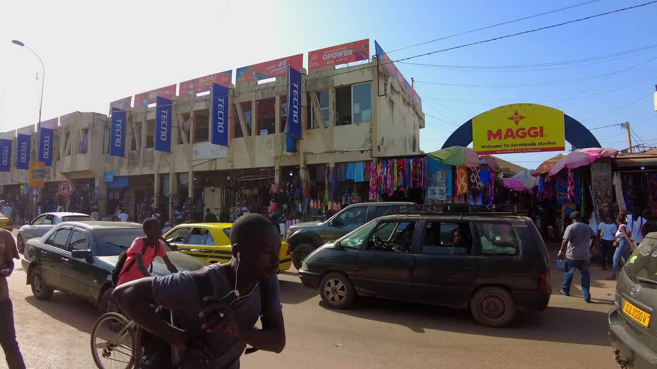 Pan shot of people in front of the entrance to the Serekunda Market in Gambia