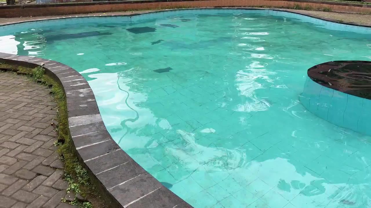Udendørs swimmingpool med krusende turkisblåt vand og flisebelagt bund