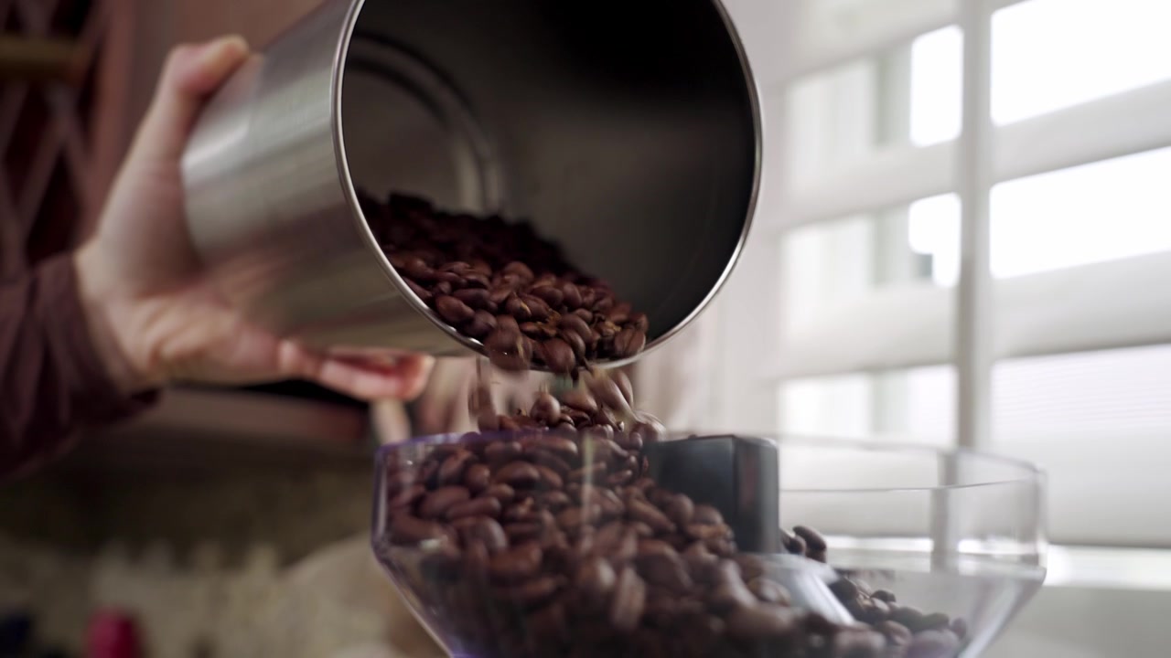 Coffee beans poured into grinder.