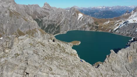 A-man-is-standing-in-a-jacket-on-the-edge-of-a-mountain-and-then-sits-down