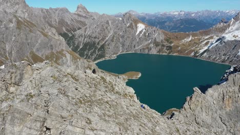 un hombre está parado con una chaqueta al borde de una montaña y luego se sienta