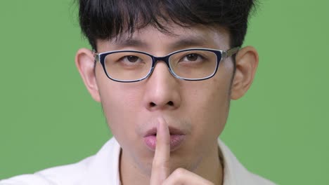 young asian businessman with finger on lips