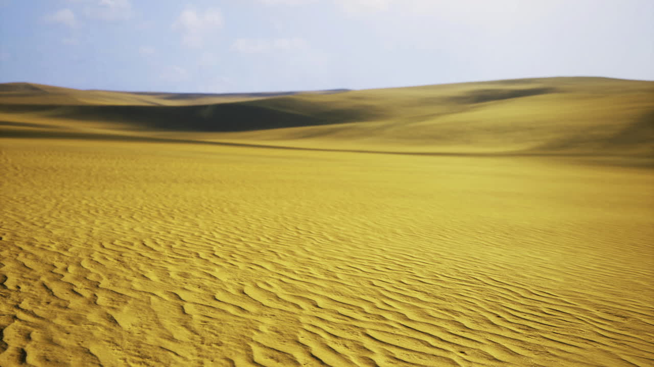 Expansive yellow sand dunes under bright blue sky in remote desert landscape