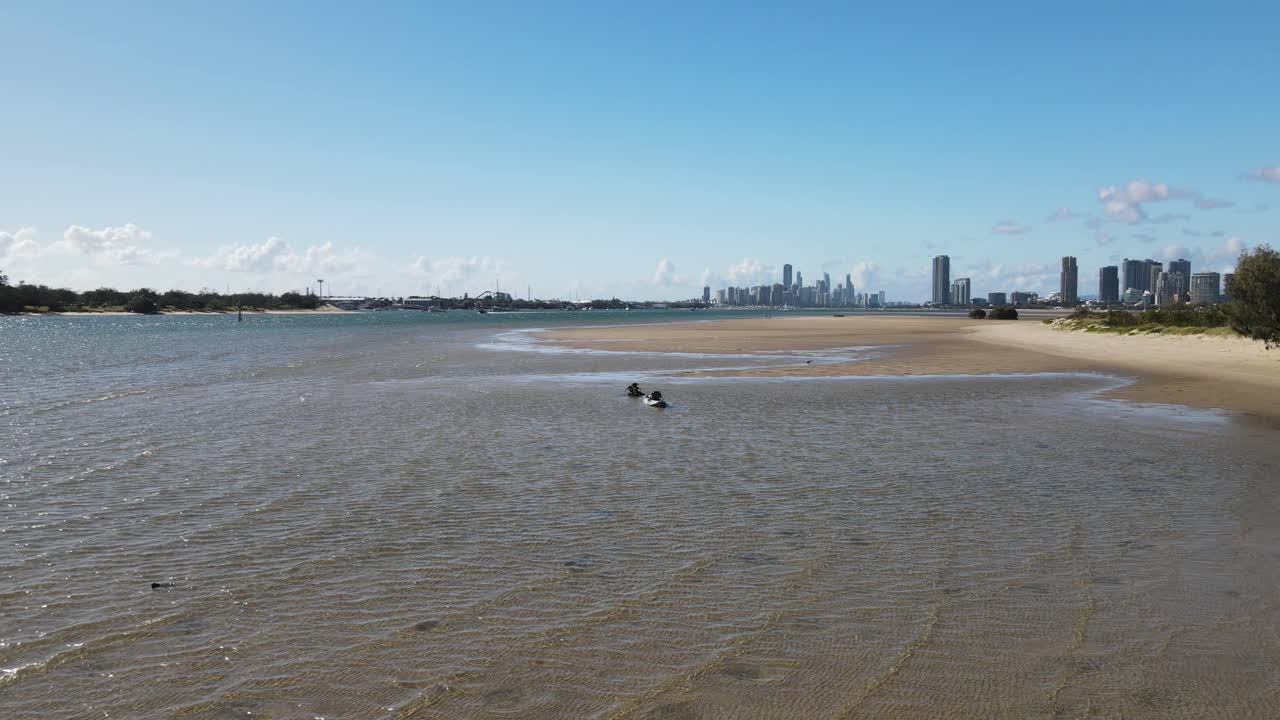 un kayak flota en una gran bahía y puerto con un horizonte urbano y una cadena montañosa en la distancia