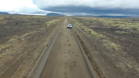 imagen aérea de un avión no tripulado siguiendo a un coche que se desvía de la carretera en islandia.