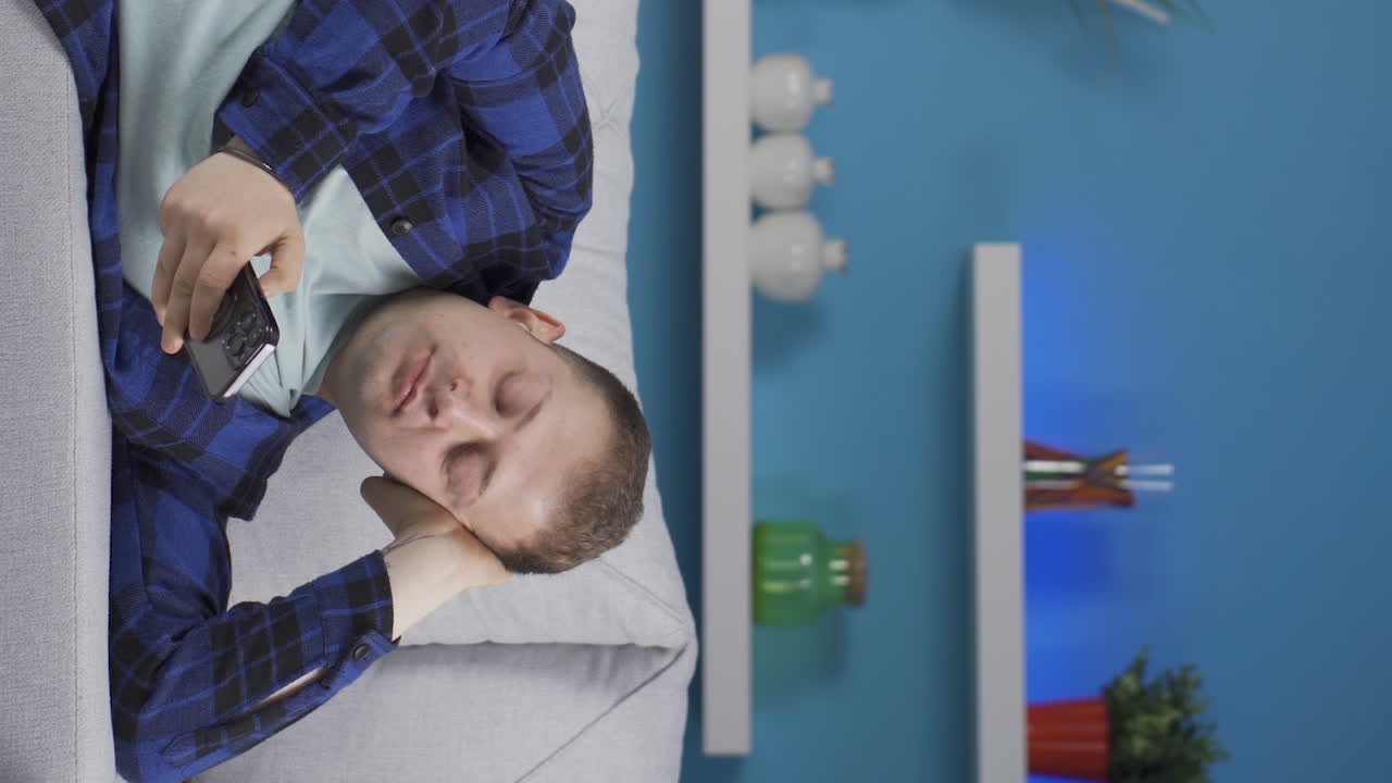 소파에 누워 있는 남자의 수직 비디오가 휴식을 취하고 있습니다.