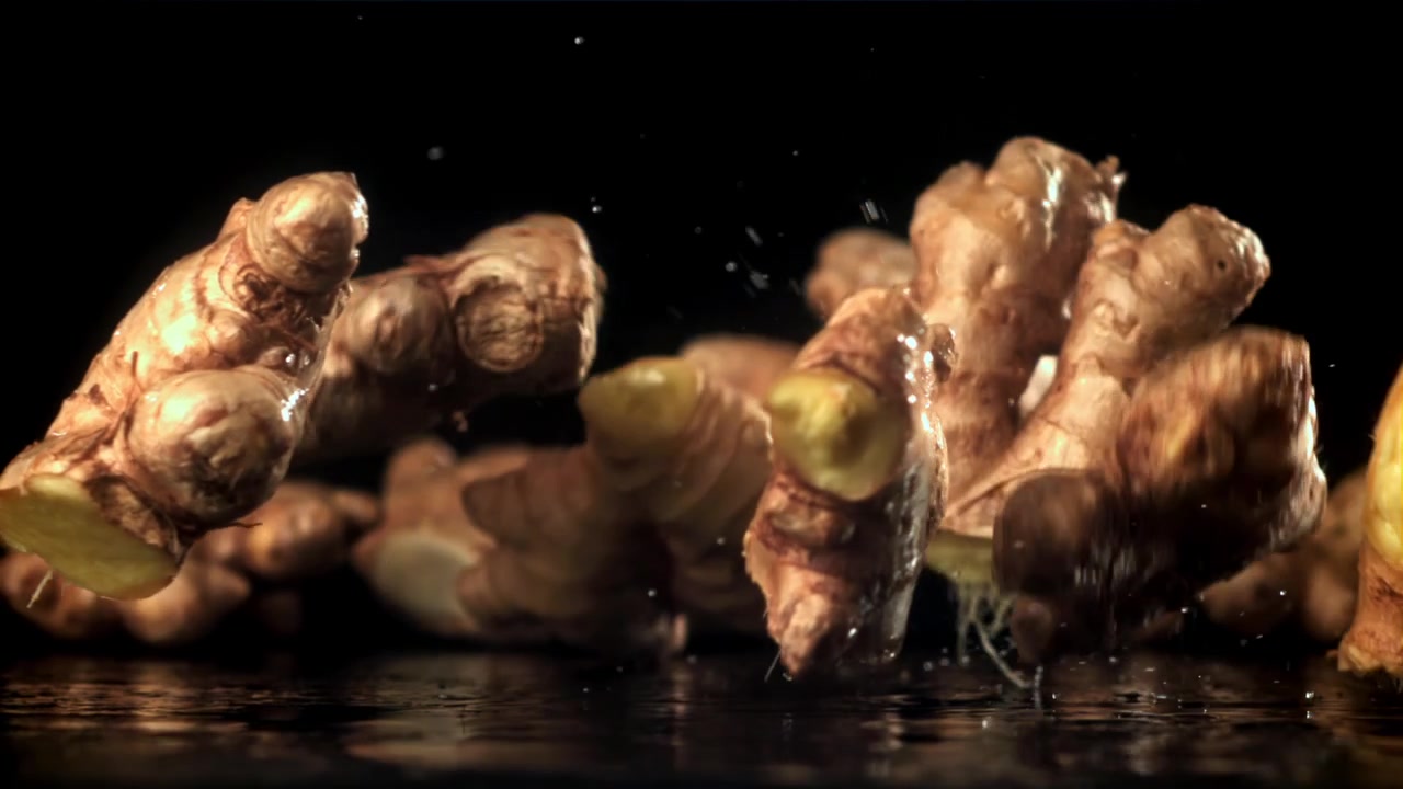 Fresh Ginger Roots Falling and Splashing Water on a Dark Surface