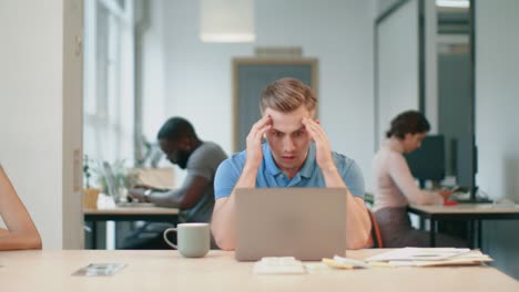 serious man watching computer at workplace. male person reading shocked news