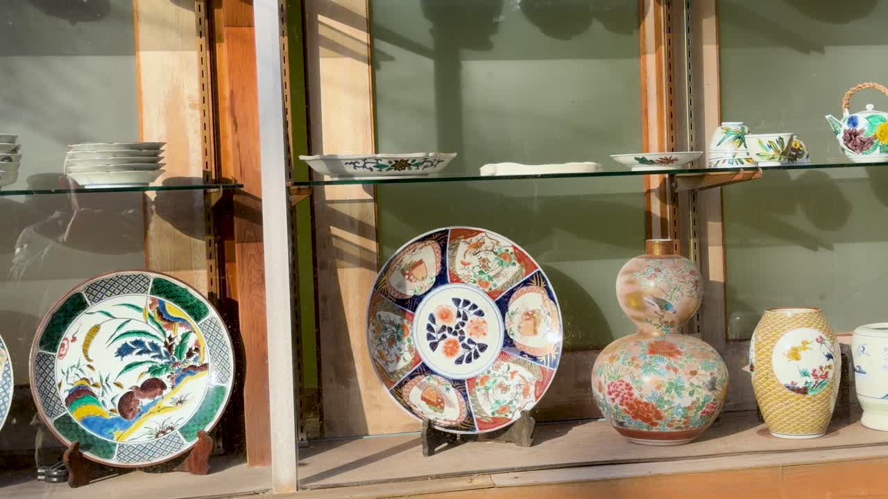 Uma panorâmica lenta por pratos e vasos de cerâmica ornamentados e pintados à mão em uma loja.