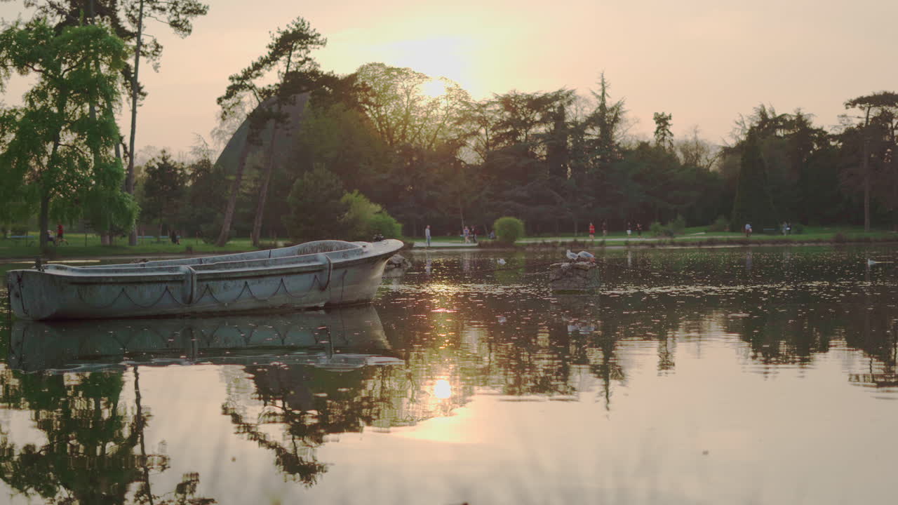 una toma estática de un bote abandonado en medio del lago del parque vincennes woods al atardecer en parís, francia