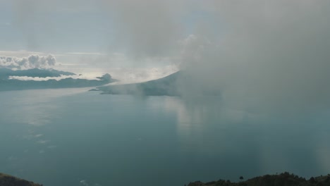 Drone-Aéreo-Volando-Alto-A-Través-De-Las-Nubes-Revelando-El-Hermoso-Lago-Azul-De-Atitlán-En-Guatemala