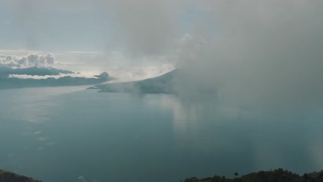 drone aerial flying high through clouds revealing beautiful blue lake atitlan in guatemala