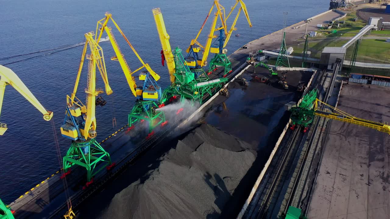 Industrial harbor view of coal yard with rainbow effect created by water spray