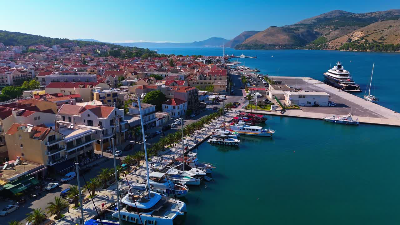 Cinematic aerial footage of Argostoli, the charming capital of Kefalonia Island in Greece. The clip captures the picturesque harbor, colorful waterfront houses, and boats gliding over the Ionian Sea