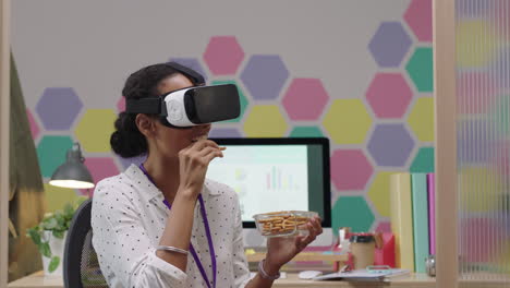 happy business woman wearing virtual reality headset enjoying entertainment on lunch break eating pretzels in colorful modern office workplace