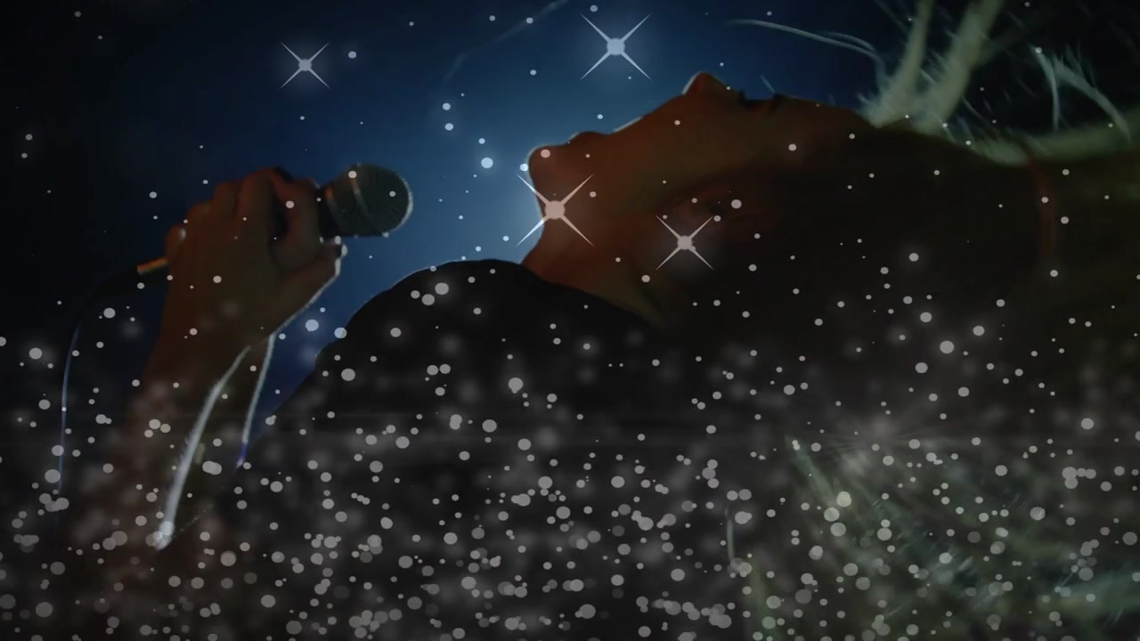Performer donna che si china verso il partner, prende il microfono e inizia a cantare tra le scintille.