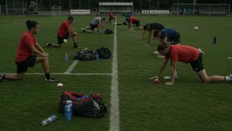 athletes engaged in stretching exercises on a soccer field, focusing on team training and physical preparation for upcoming competition