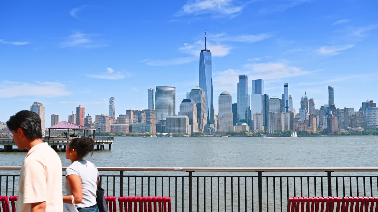 Waterfront walkers with skyline. Visitors stroll along the waterfront promenade, enjoying scenic views of the city skyline and waterfront activities