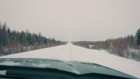 Truck-POV-Driving-Down-a-White-Snow-Covered-Winter-Highway-with-Trees-on-Both-Sides