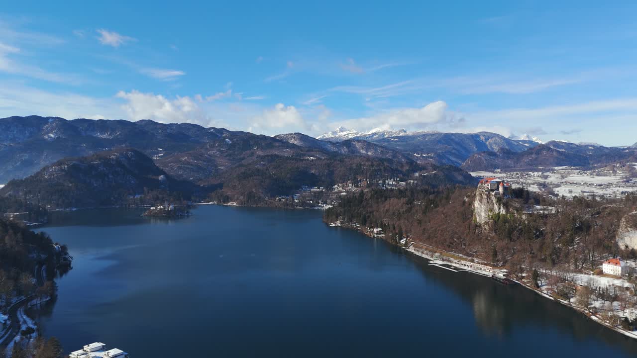 Vista aerea con drone del Lago di Bled in inverno con montagne e paesaggio suggestivo, che si muove lentamente sopra il lago con una vista panoramica sulla natura.