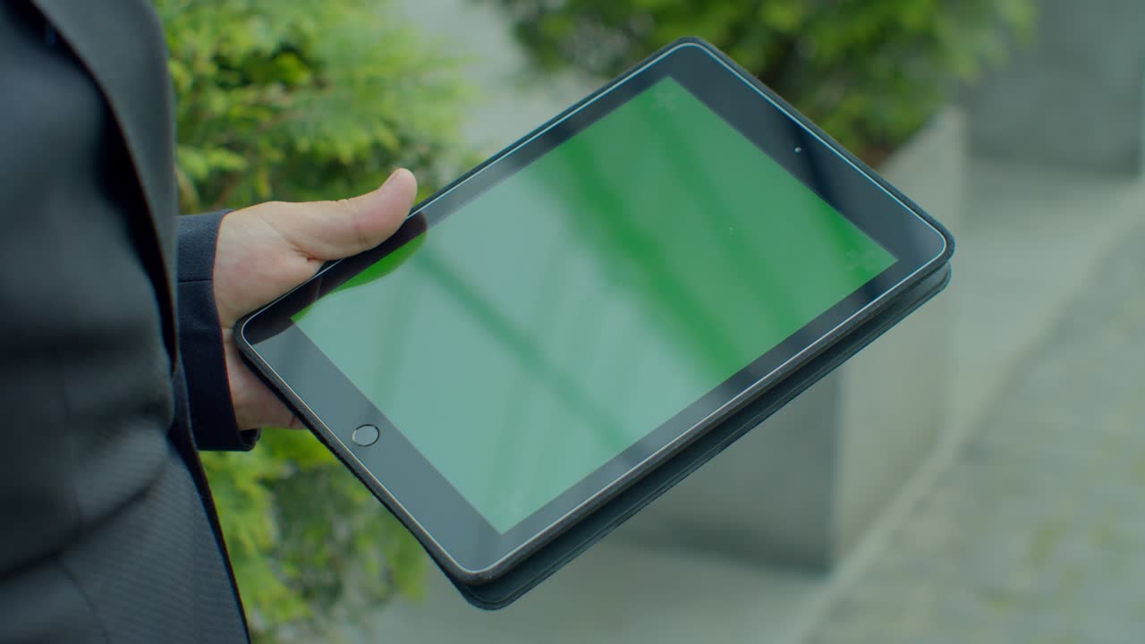 hombre de negocios navegando por internet en línea en una tableta digital al aire libre. hombre de negocios de cerca trabajando en el touchpad en la calle. manos masculinas escribiendo en el pad con pantalla verde en cámara lenta.