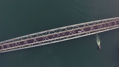 4k aerial birds eye overhead top down view of the adomi bridge on the volta lake or volta river at atimpoku, ghana, west africa with cars driving over the bridge and a boat cruising under