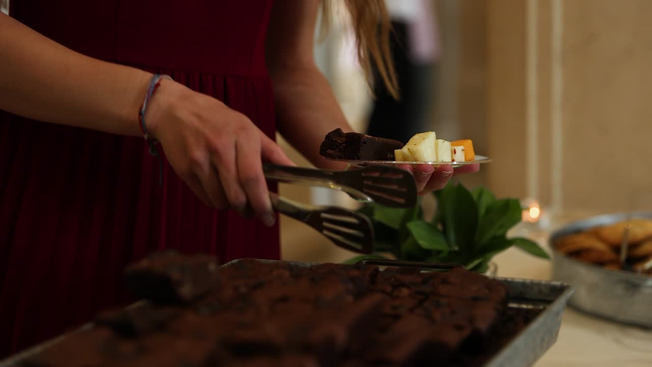 Person with Tongs Serving Brownies and Other Hors d'Oreuvre at Catered Wedding Reception Party